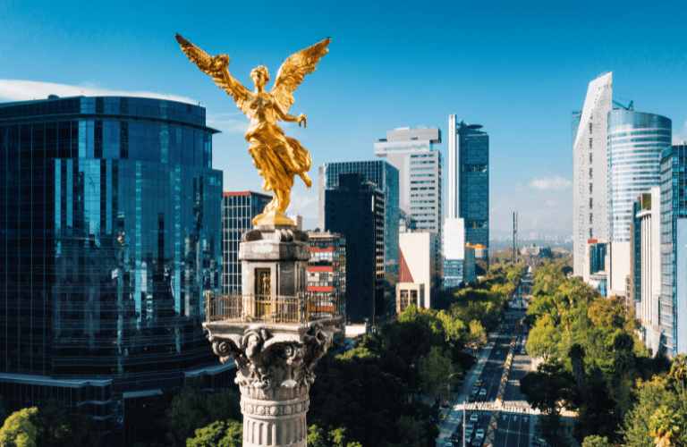 a statue of a woman with wings on top of a pillar with a city in the background
