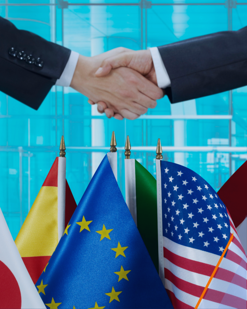 A handshake between businessmen with international flags in the background